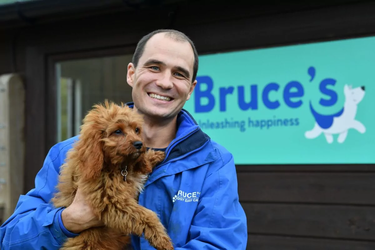 Bruce casalis holding a puppy in front of a Bruce's sign