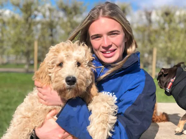 Centre manager at our Woodcote Green doggy day care centre hugging a cockapoo